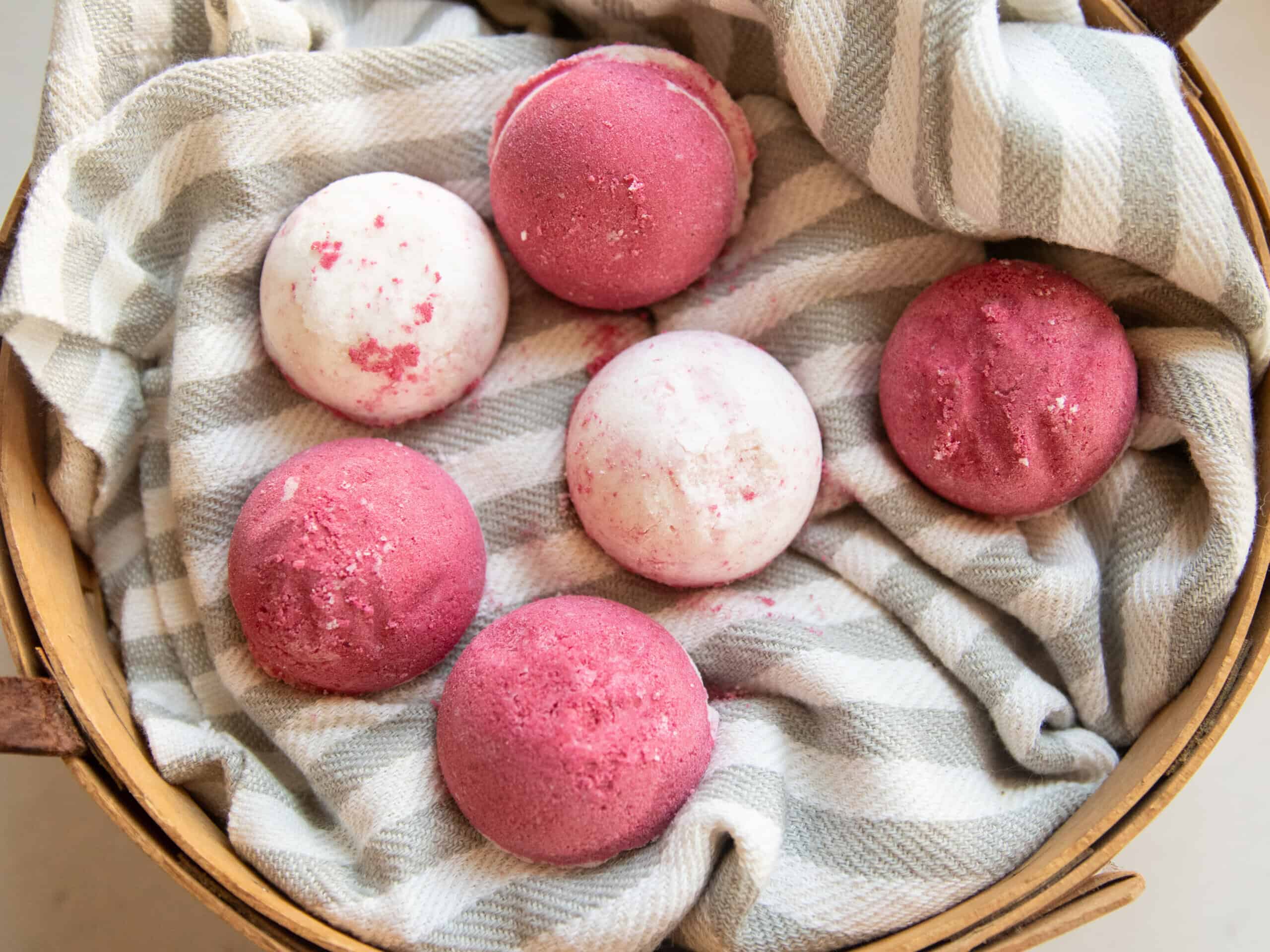 Homemade bath bombs in a basket with a striped towel. 