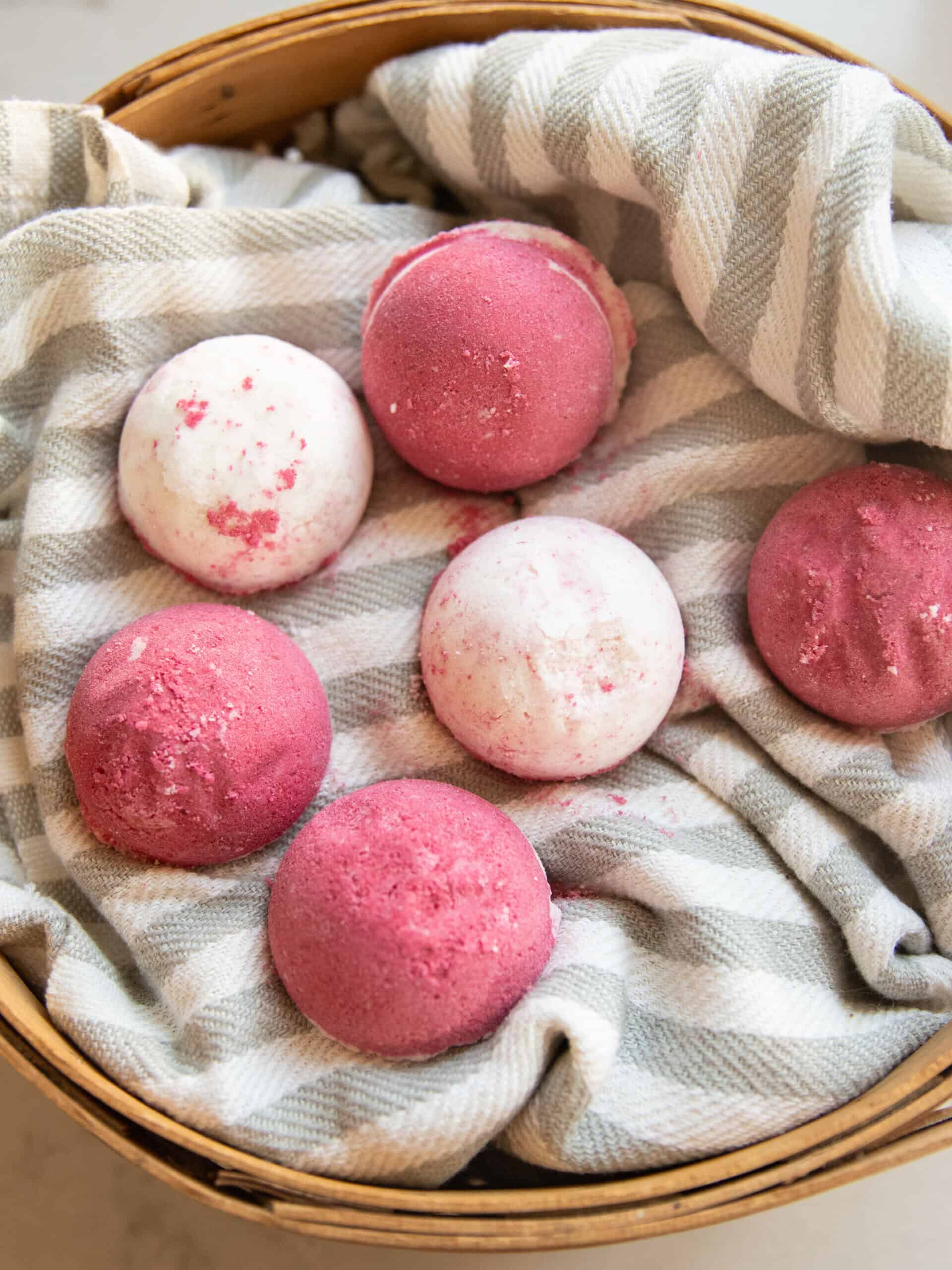 Pink Christmas bath bombs in a basket with a towel. 