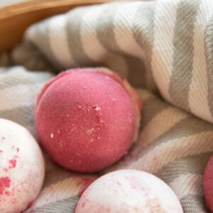 A close-up of a pink bath bomb on a striped towel.