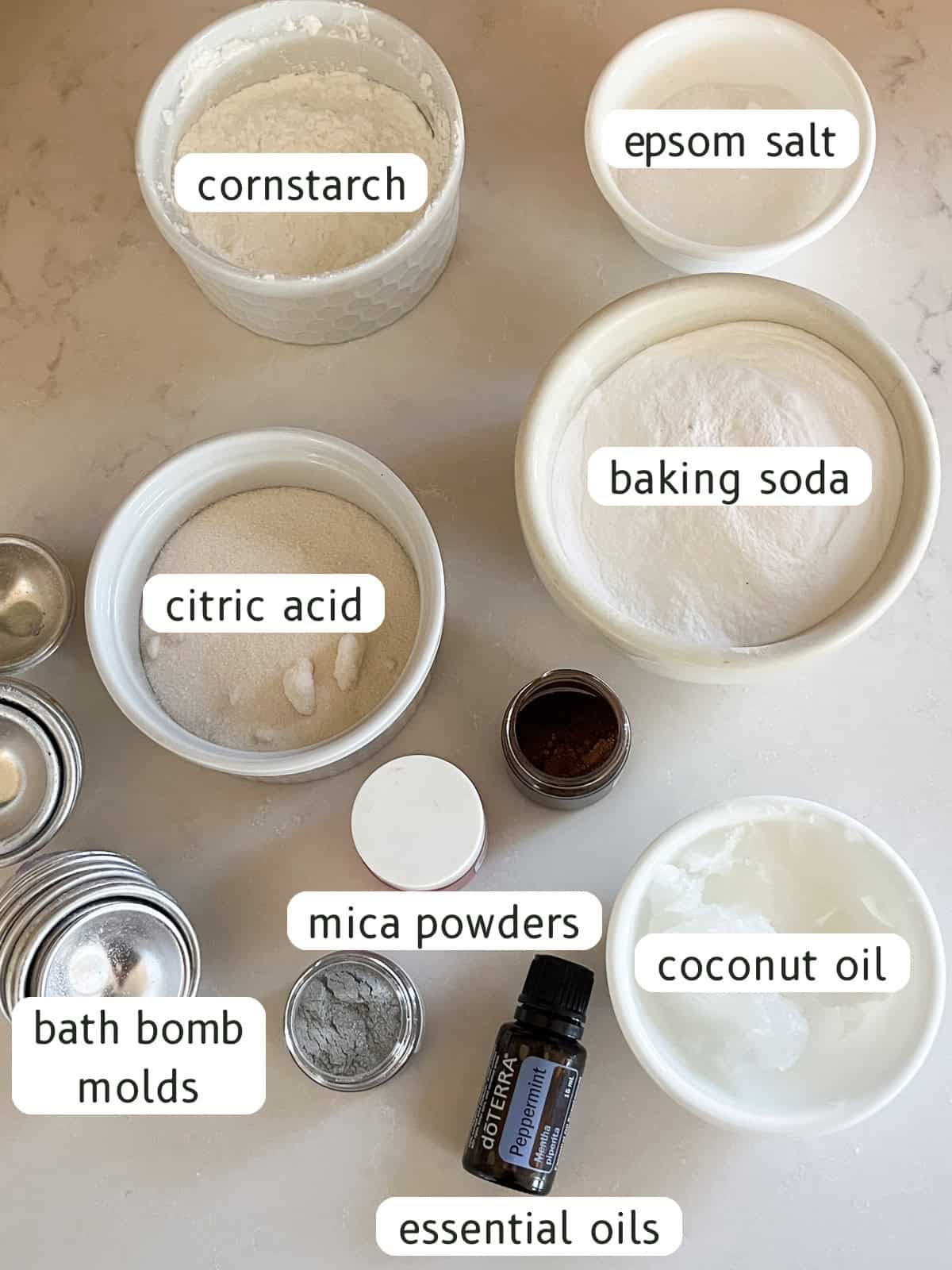 Homemade Christmas bath bomb ingredients labeled on a white background.